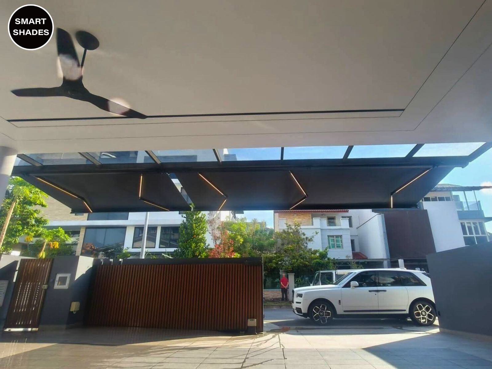 Wide retractable awning creating shade for a car porch and patio