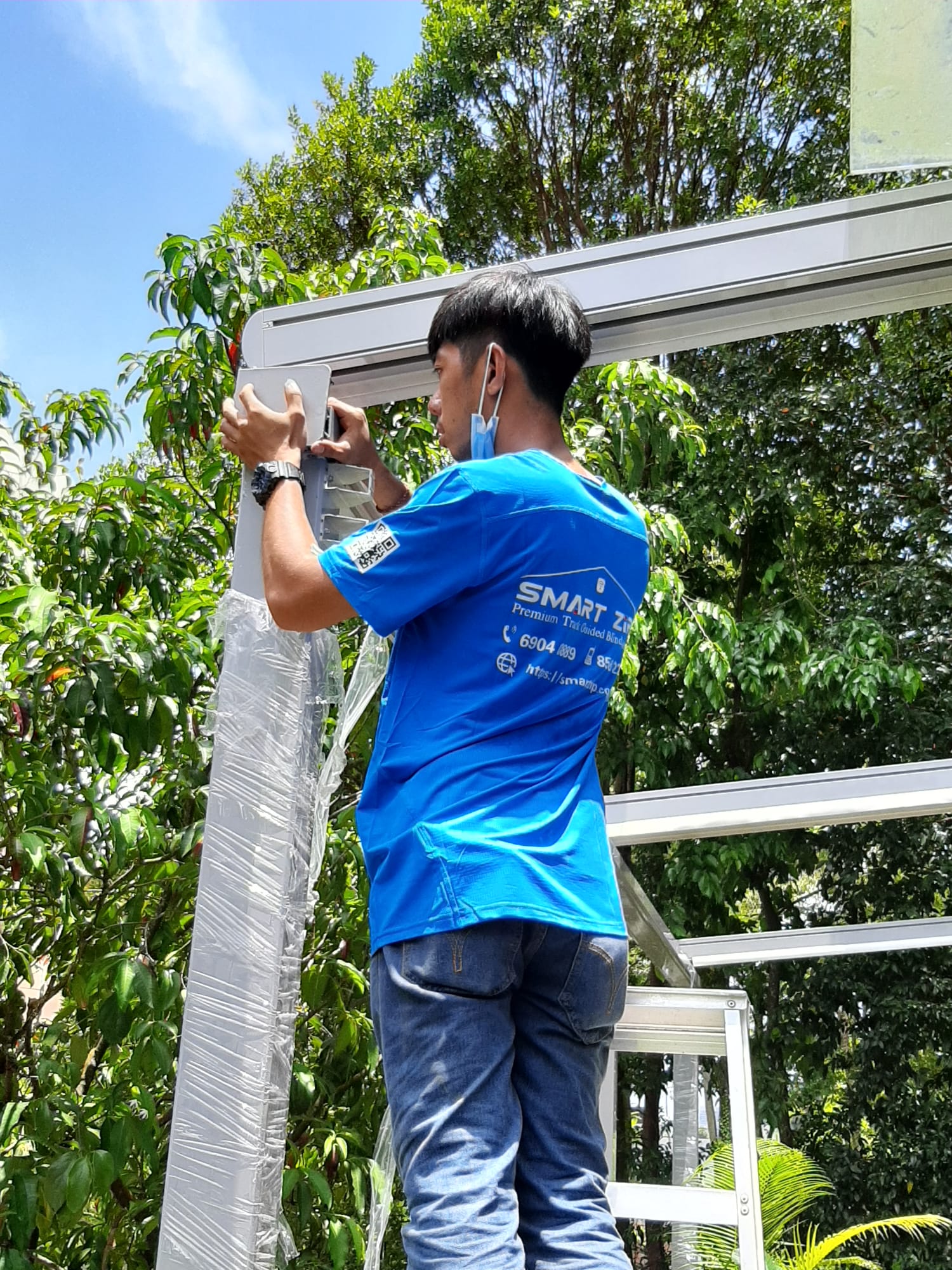 Installer measuring and preparing a pergola frame at a Singapore property