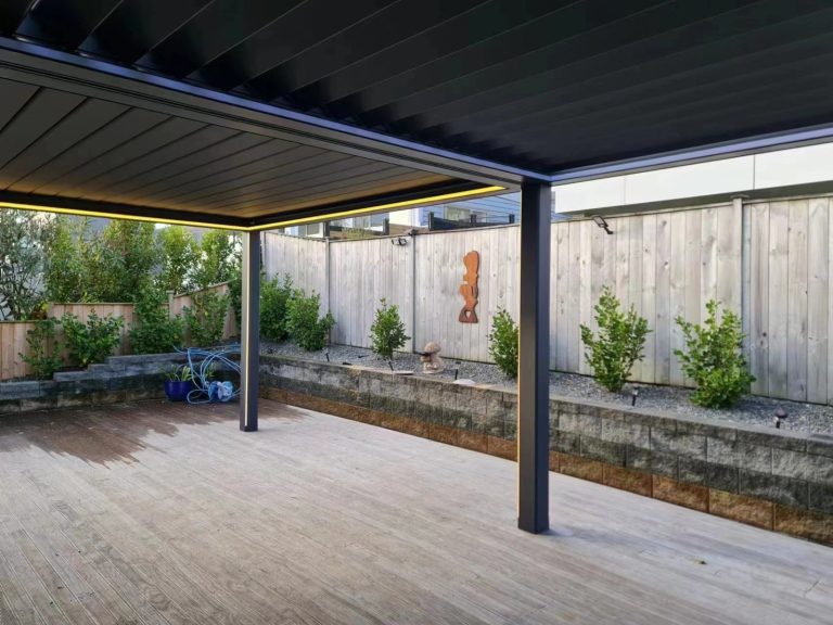 Dark pergola frame above a garden deck — aluminium pergola
